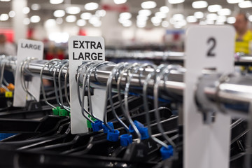 Close up of a clothing rack with plastic hangers showing extra large clothing size tags