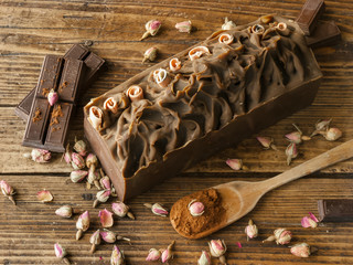 Chocolate bar soap and roses on a brown wooden background