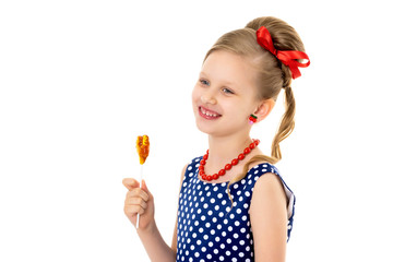 A little girl licks lollipop.