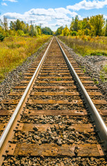Long train track 'railroad' in the countryside extending on until it disappears, scenic autumn colors abound.
