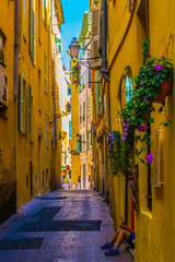 People are strolling through a narrow street in the center of Nice, France