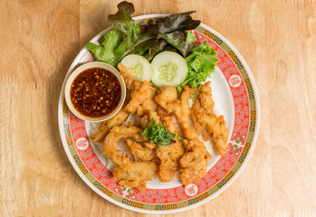 Fried chicken place on top the rice with cucumbers and sauce.