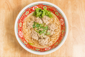 Close up of Instant noodle with meat ball and green Coriander on wood table