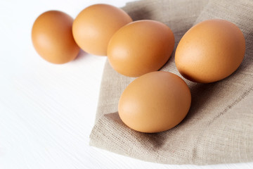 Brown chicken eggs on burlap on a white background - 219888863