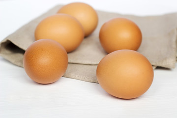 Brown chicken eggs on burlap on a white background - 219888877