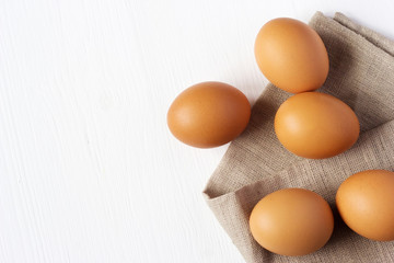 Brown chicken eggs on burlap on a white background