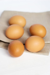 Brown chicken eggs on burlap on a white background