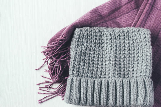 Gray woolen knitted hat and pink scarf on a white background