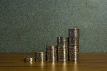 Savings, increasing columns of gold coins, piles of gold coins arranged as a graph on working desk,...