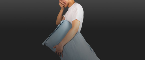 Man yawning holding a pillow with black gradient background
