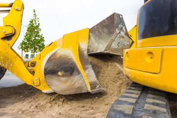 The yellow front end loader dumping stone and sand in a mining quarry