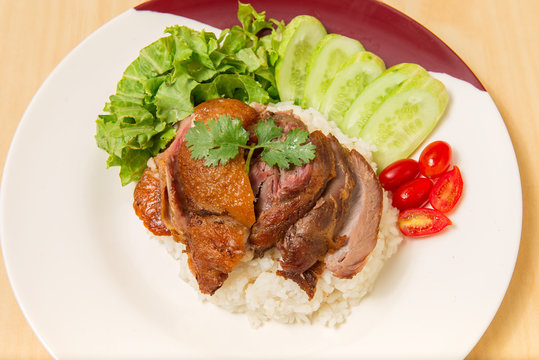 German pork knuckle with rice, vegetable and fruit served with sauce on wooden table.