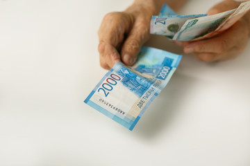 The hands of the old man hold Russian large bills of denomination of 1,2,5 thousand.
