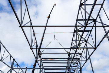 The mobile plan builds and raises a metal structure for building a large building of metal structures using new modern technologies against the blue sky
