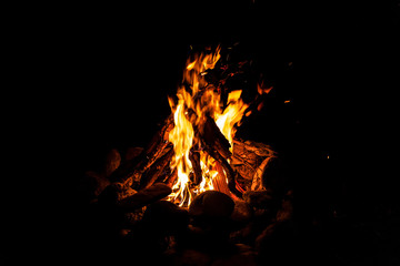 Close-up of a fire with an orange and red flame burning in the dark