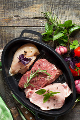 Fresh raw meat. Different types of raw pork meat, chicken fillet and beef with vegetables and herbs on wooden table. Top view. Copy space.
