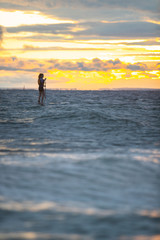 Fototapeta na wymiar Beautiful woman stand up paddle boarding at sunrise or sunset