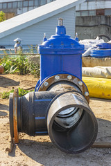 Elements of the pipeline, plastic pipes, cast iron valve at a construction site