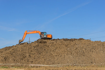 Obraz premium Orange excavator loads the land on a construction site..