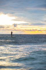 Fototapeta na wymiar Beautiful woman stand up paddle boarding at sunrise or sunset