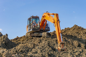 Obraz premium Orange excavator loads the land on a construction site..