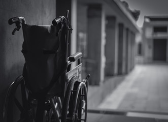 Wheelchair folded beside the wall. Sad news at the hospital concept. Depression with aging society. Lonely empty wheelchair. Medical equipment for service patient and assistant disabled elderly people