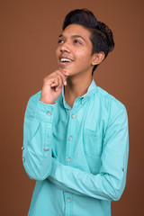 Young Indian boy wearing blue shirt looking smart against brown 