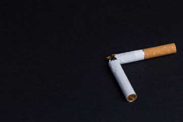 Broken cigarette on black background close-up