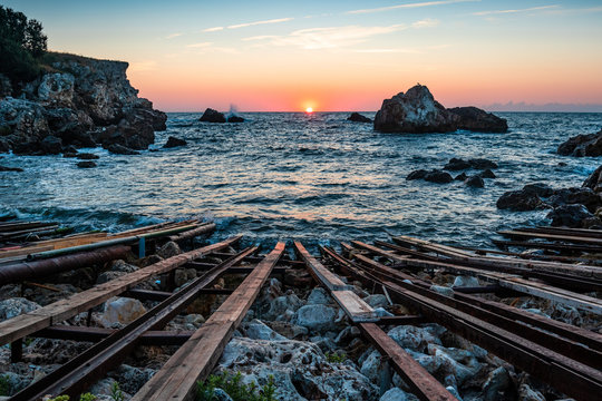 sunrise at rocky bay at sea with steel and wood bo, at rails bulgaria