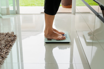 old woman standing on weight scale in living room