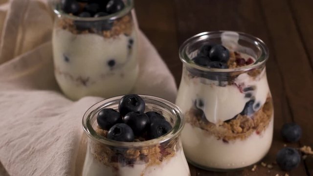 Yogurt parfait with blueberry and granola. Healthy breakfast concept served in mason jar with decorative spoons on wooden table.