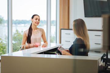 Visit to a beauty salon. Cheerful delighted woman smiling while wanting to make an appointment to the beauty salon