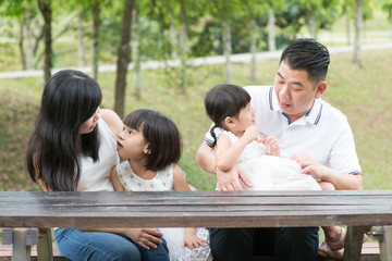 Asian family bonding outdoors with empty table space.