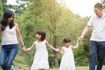 Naklejka na ściany i meble Asian family hold hands and walking at outdoor park.