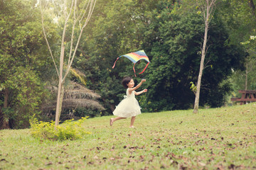Happy little Asian girl flying kite at park.