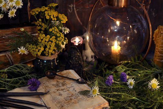 Still life with retro lamp, old book, black candles and healing herbs with flowers. Mystic background with ritual esoteric objects, occult, fortune telling and halloween concept