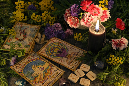 Still life with old tarot cards, black candle, runes, healing herbs and flowers. Mystic background with ritual esoteric objects, occult, fortune telling and halloween concept