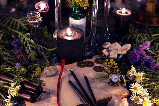 Still life with healing herbs and flowers, old book and black candles. Mystic background with ritual esoteric objects, occult, fortune telling and halloween concept