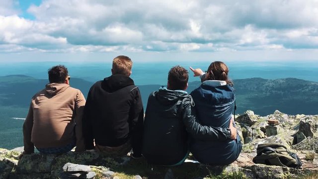 A group of friends, tourists resting on top of the mountain