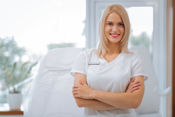 Favourite job. Delighted positive woman smiling to you while working as a cosmetologist in the...