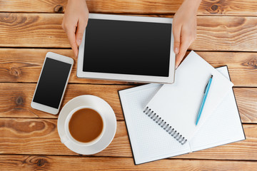 Girl hands with digital tablet and cup of coffee on a wooden table