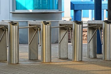 a row of metal turnstiles on the sidewalk at the station