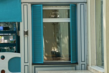 one window with blue shutters on a gray wall