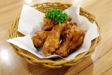 Fried chicken wings in white plate on wooden table..