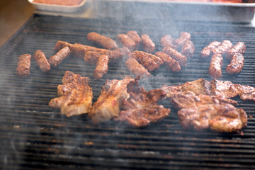 Street food being made in state fair. Traditional meat and sausages grilled in open air market for people. First barbecue party outdoors in spring