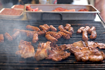 Street food being made in state fair. Traditional meat and sausages grilled in open air market for people. First barbecue party outdoors in spring