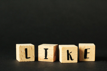 Obraz premium Word concept - LIKE build from wooden cubes with letters, selective focus, black background, free copy space