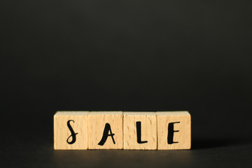 Business Concept: word SALE build from wooden cubes with letters, selective focus, black background