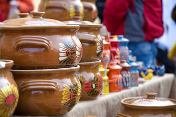 Traditional Romanian painted clay pots used for Easter meals. Decorations and ornaments on bowl. Beautiful kitchen decor. People buying kitchen supplies in local market