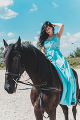 Obraz premium Romantic scene woman with a horse in the countryside. Concept of horse and human. Portrait of vintage style artistic woman walking with horse outdoors in turquoise dress